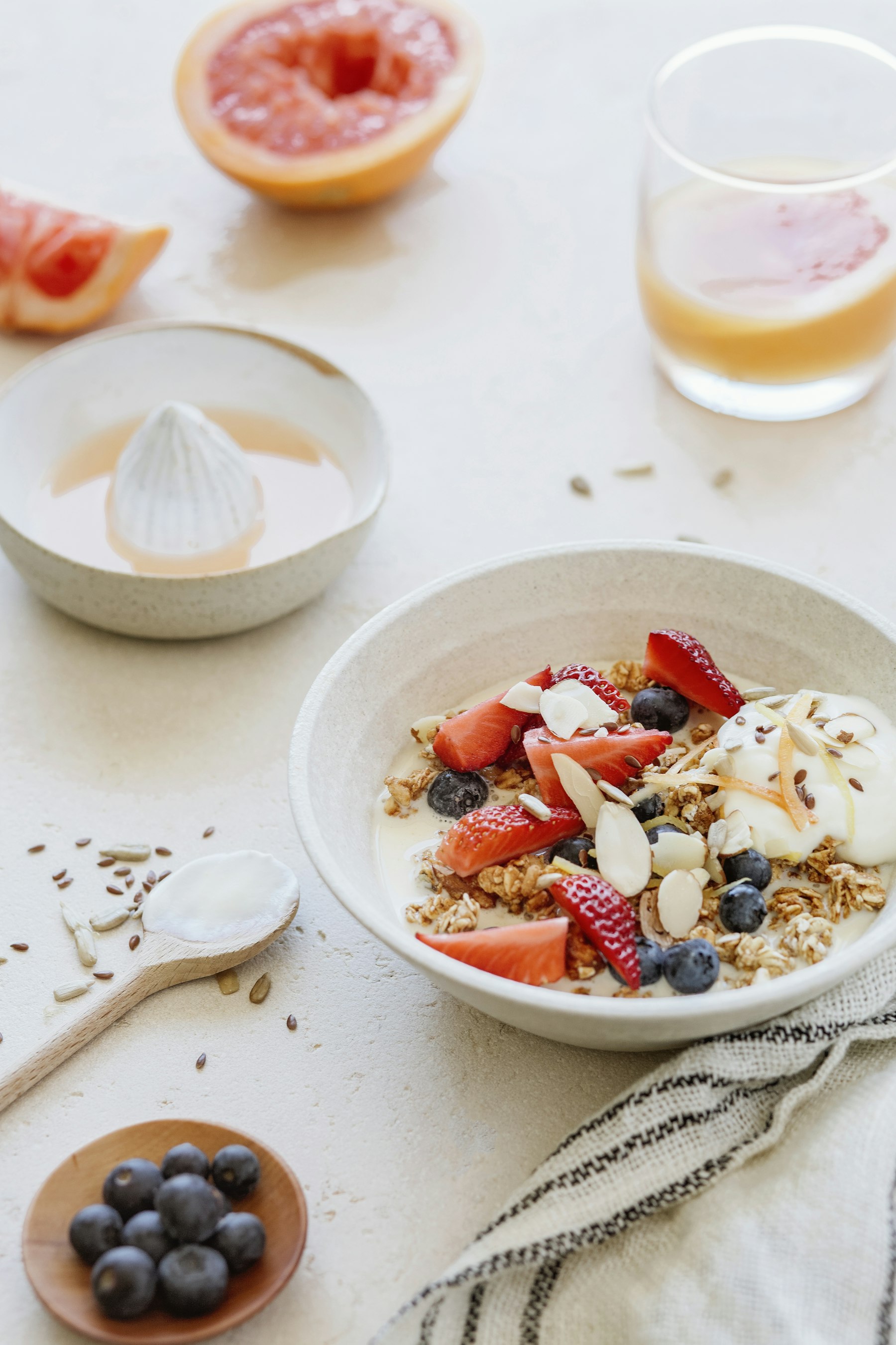 Skål med yoghurt, granola, jordgubbar och blåbär på en ljus bordsskiva.
